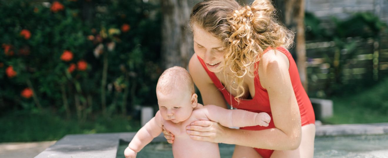 mother holding her baby in the swimming pool